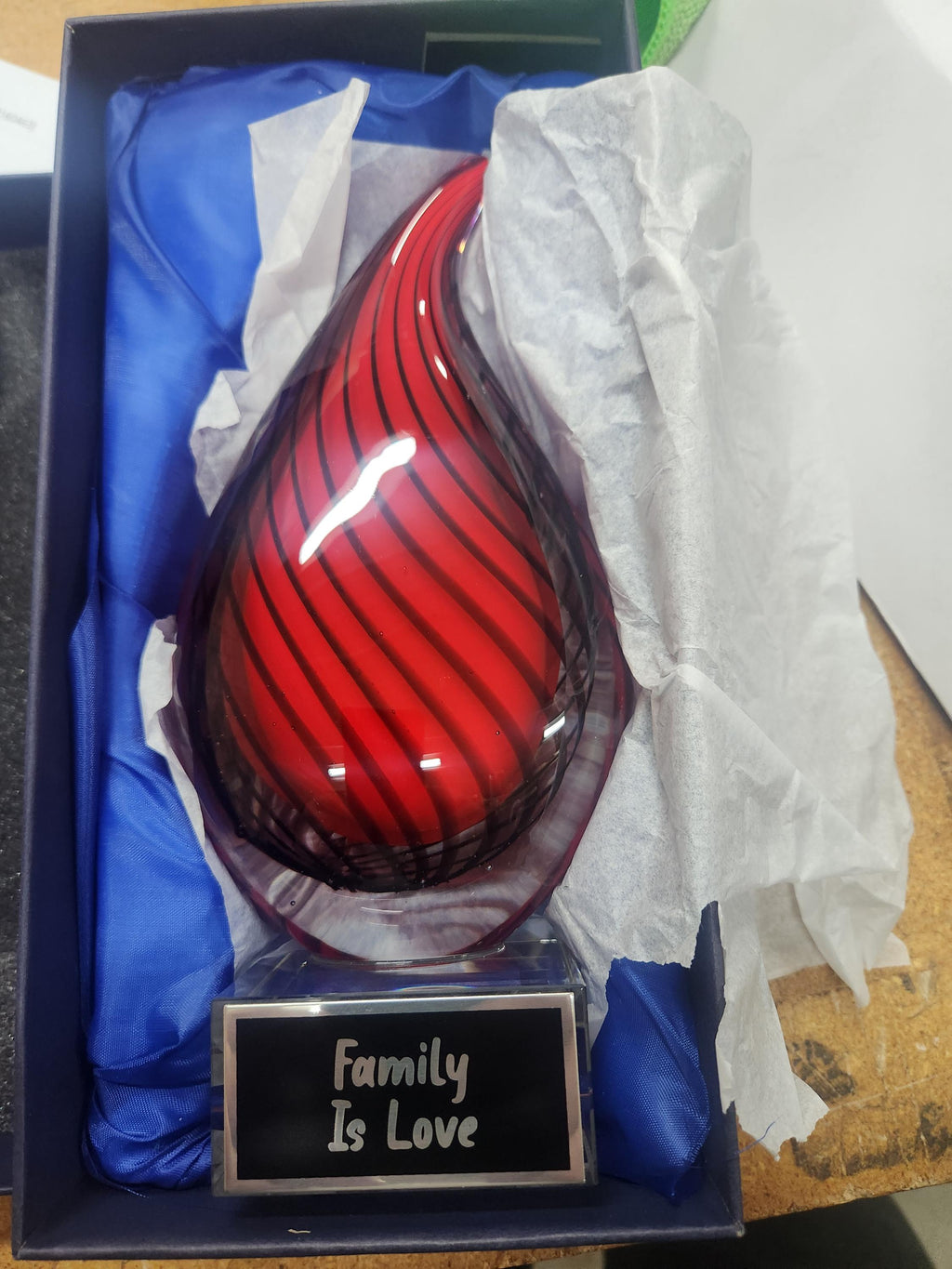Red glass teardrop award with engraved plaque reading 'Family Is Love' in gift box.