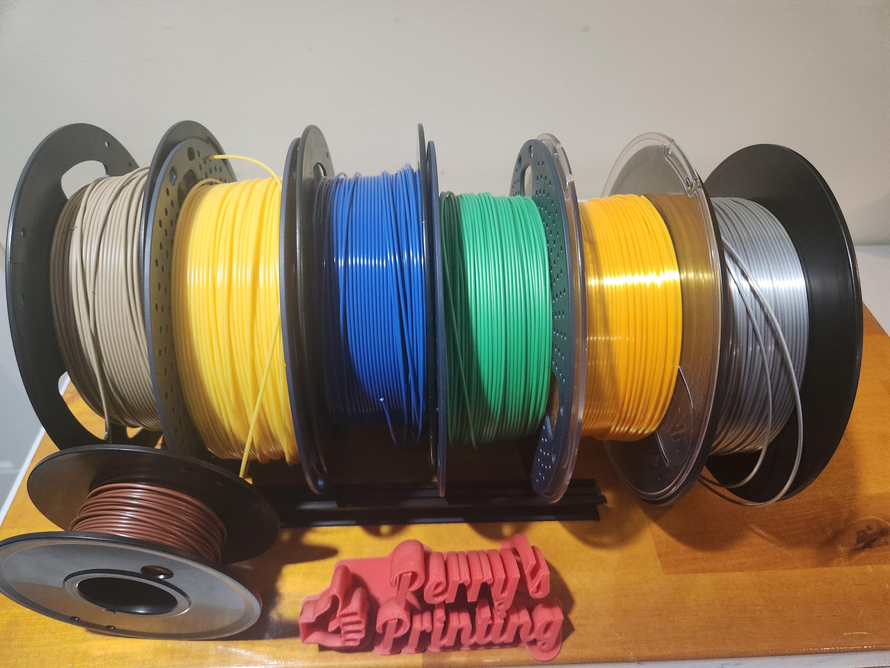 Assorted 3D printer filament spools in various colors on a rack, desktop setup