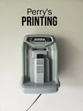 Wall-mounted battery charger below 'Perry's PRINTING' text on white background.