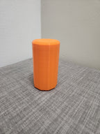 Orange 3D printed polygonal container on a gray fabric surface