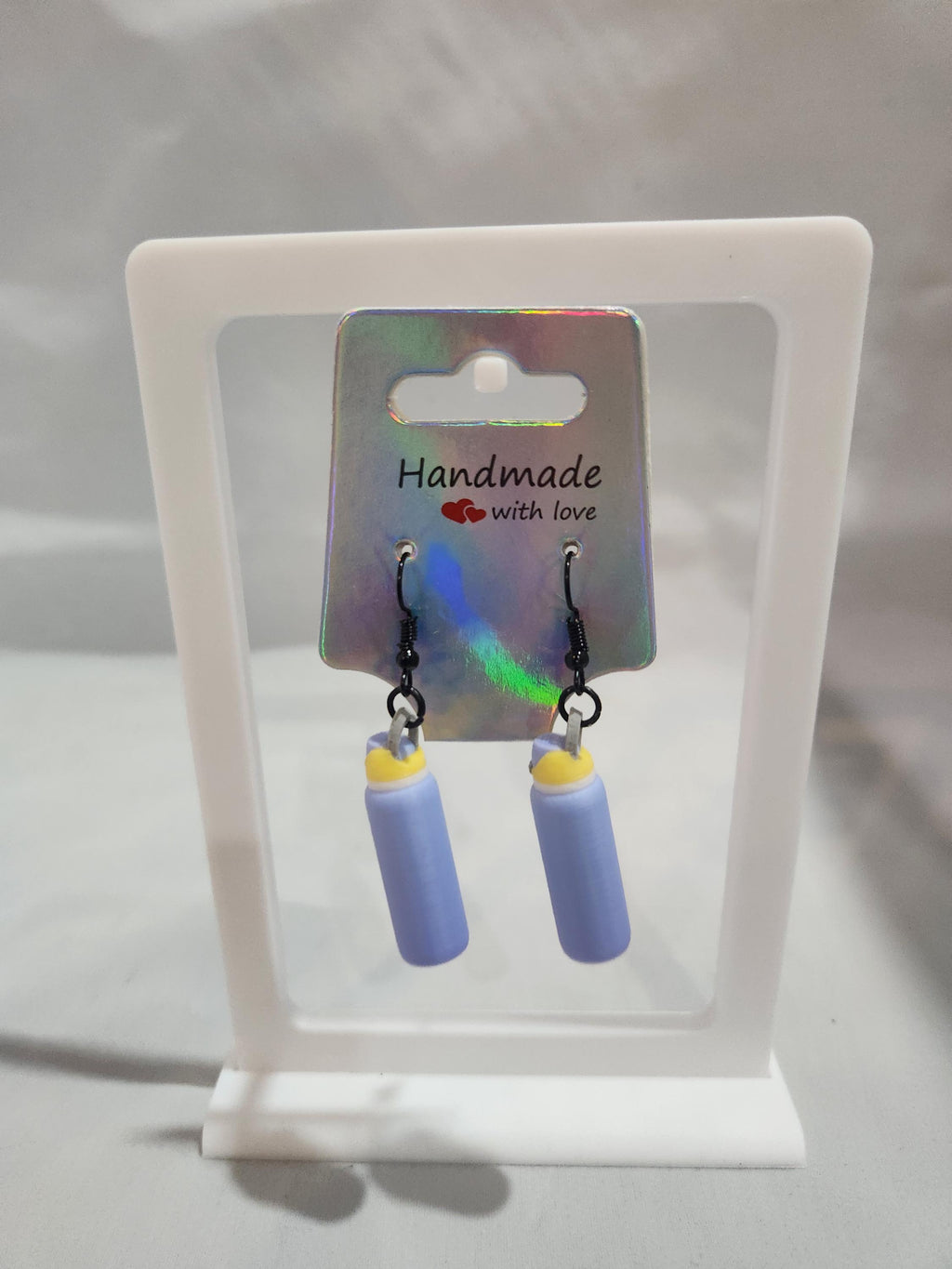 Handmade 3D printed purple candle earrings on display with iridescent backing card