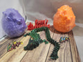 3D printed dragon models, colorful eggs, and Perry's Printing sign on wood surface