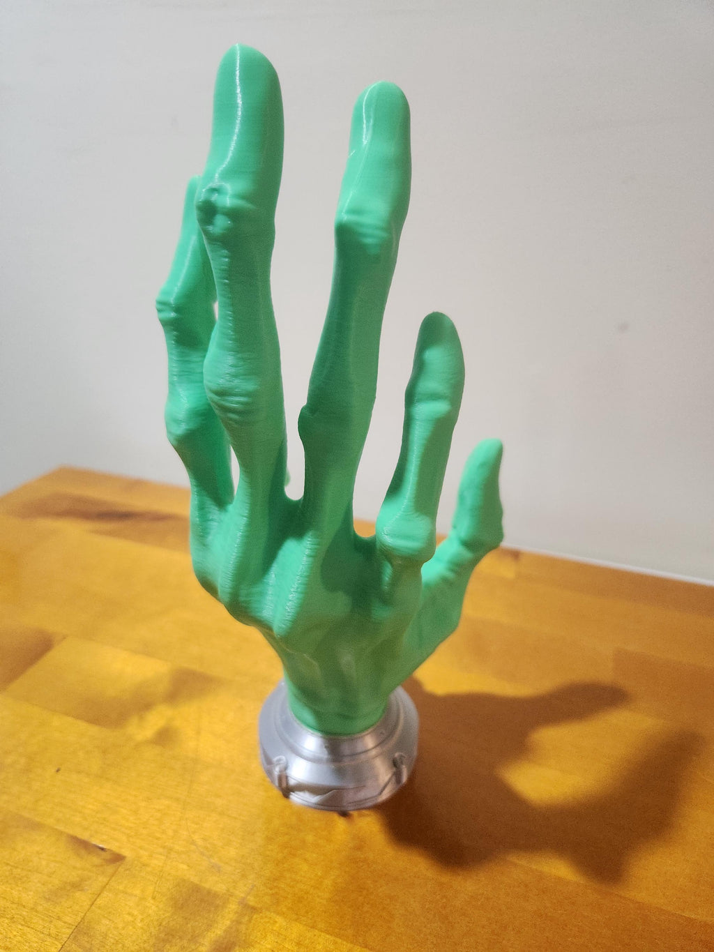 Green 3D printed hand sculpture on a wooden surface, custom design decor