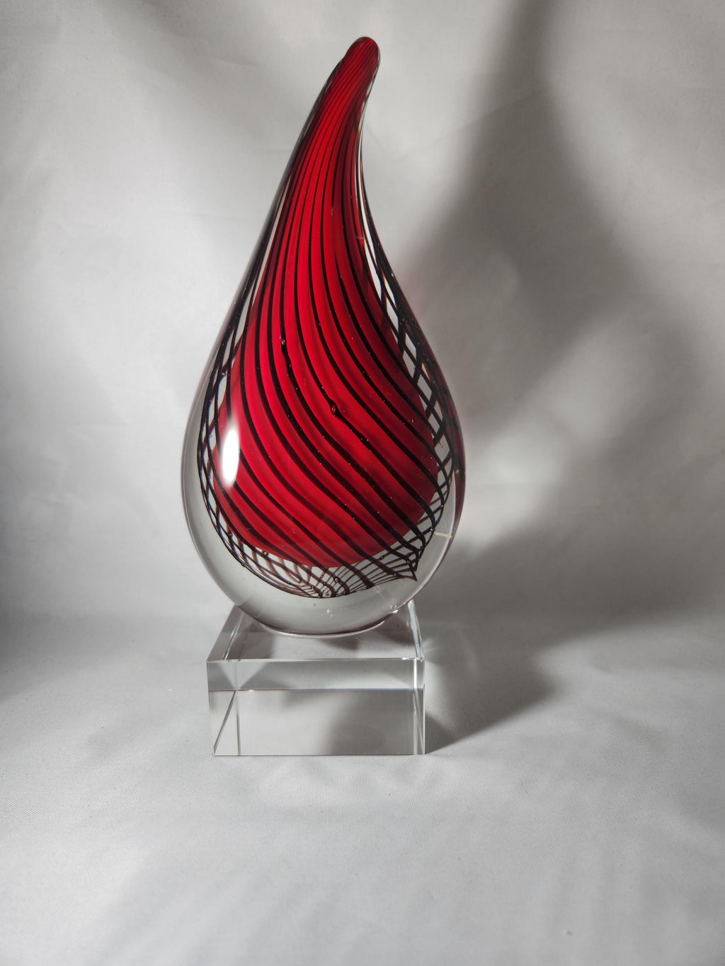 Red and black swirled glass teardrop award on clear base, custom engraving display.