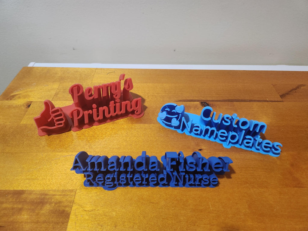 3D printed custom nameplates in blue and red on a wooden surface, including personalized nurse sign.