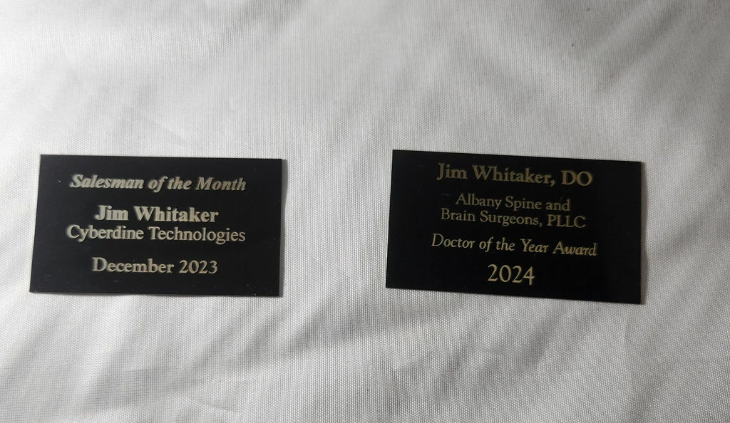 Two engraved award plaques with gold text on black background for sales and doctor achievements.