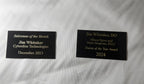 Two engraved award plaques with gold text on black background for sales and doctor achievements.