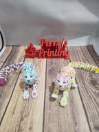 3D printed colorful leopard figurines and a red Perry's Printing sign on wood background