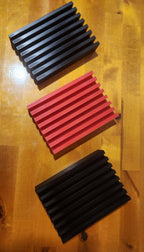 Three rectangular 3D printed slotted organizers in black and red on a wood surface