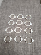 Set of twelve white 3D printed plastic frames with screw holes on gray fabric surface