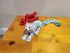 3D printed leopard figurine with colorful spots on a wooden table, custom print in background