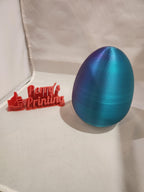 Blue 3D printed egg and red 3D printed Perry's Printing sign on white background