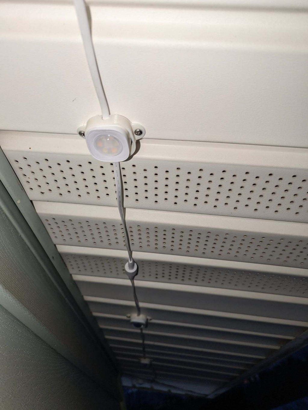 Close-up of LED soffit lights installed under perforated eaves with visible wiring