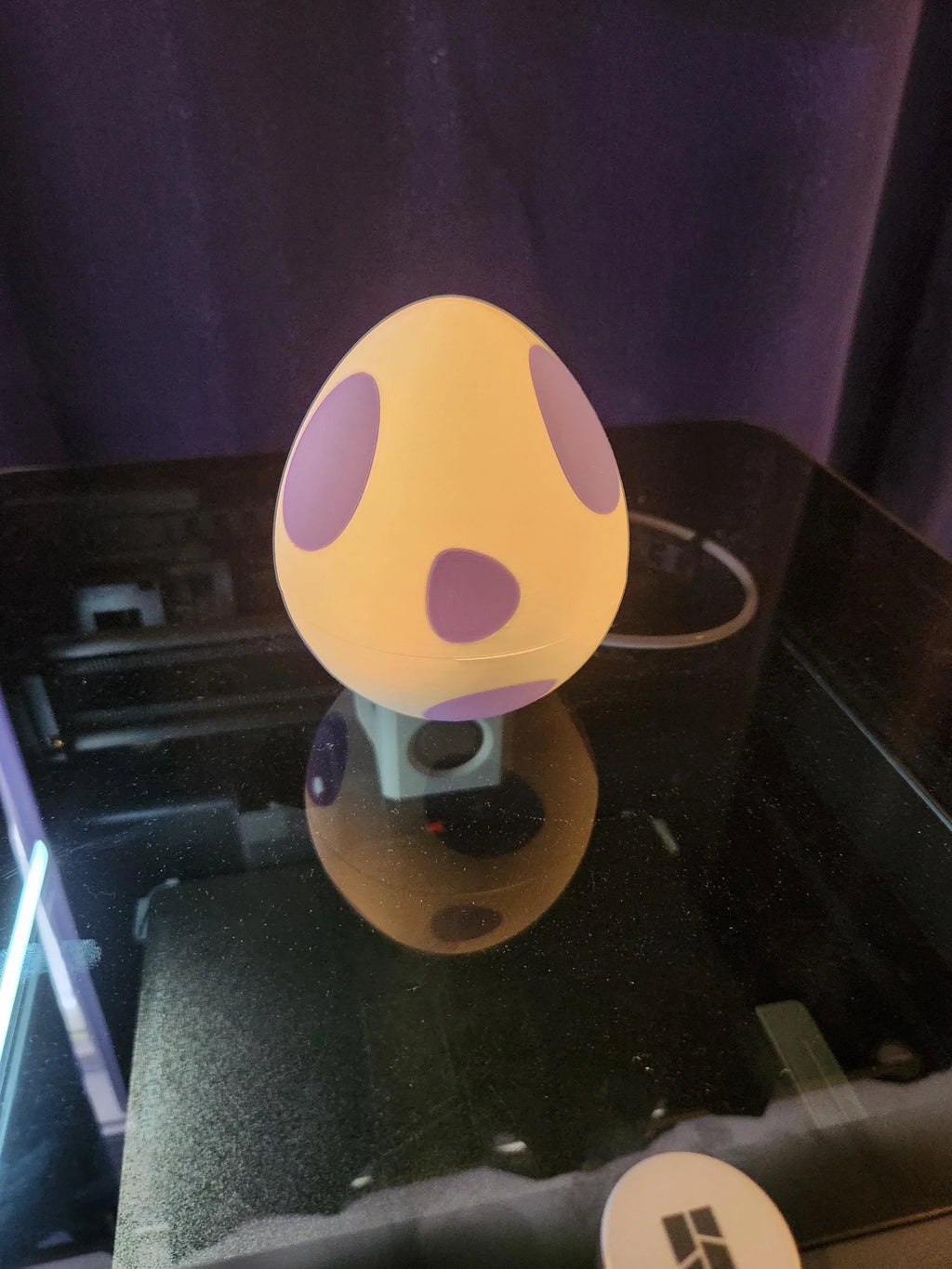 3D printed yellow egg with purple spots on a printer bed, custom printing example