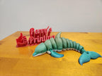 3D printed flexible dolphin figure and red Perry's Printing sign with thumbs up on wood table