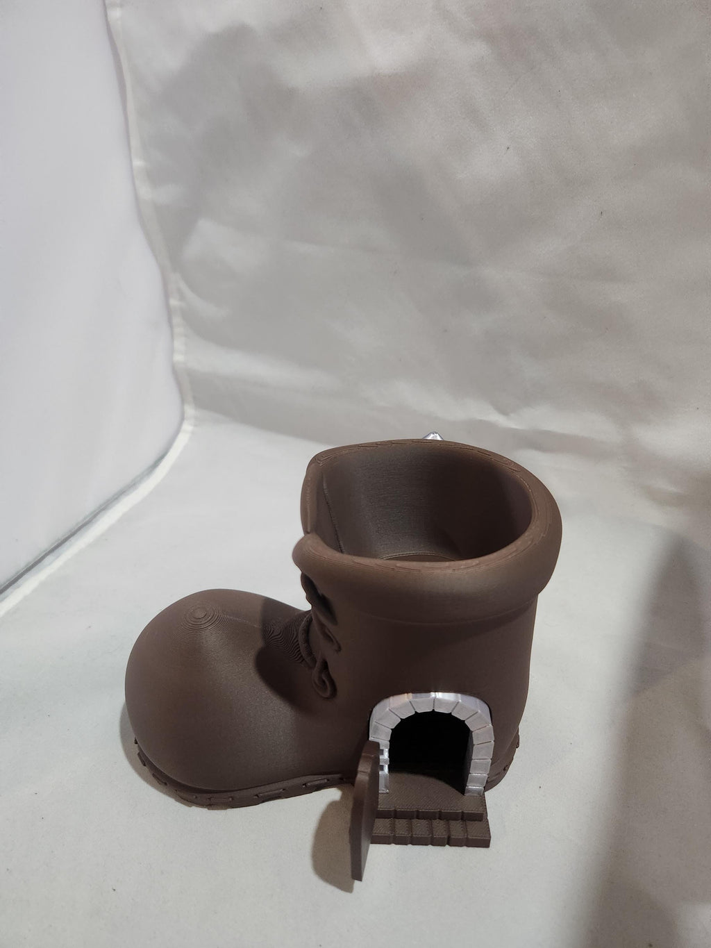 3D printed brown boot-shaped container with mini door and brick archway, tabletop decor
