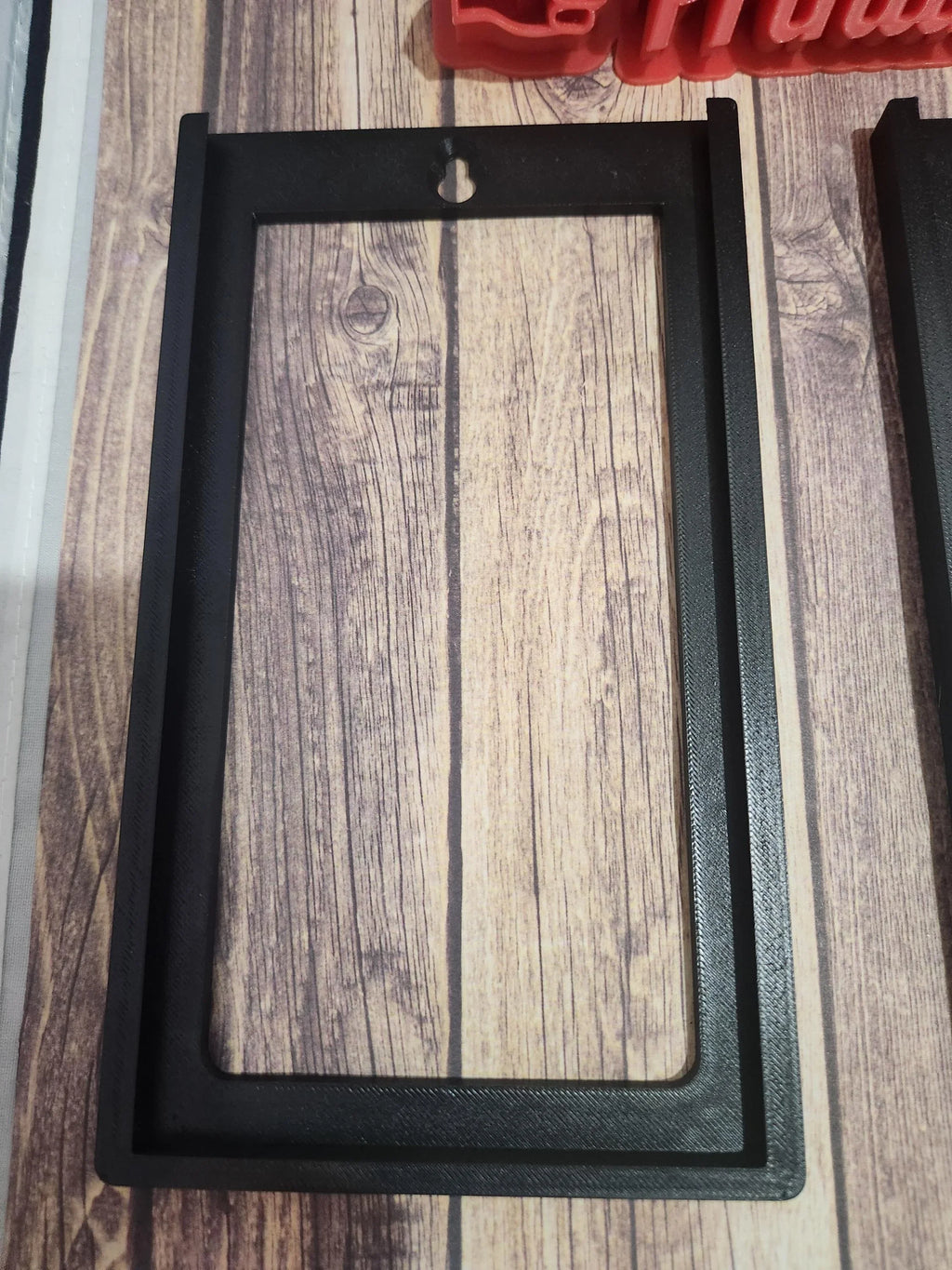 Black 3D printed rectangular frame with keyhole slot on wood surface