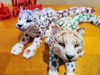 3D printed articulated leopard figurines with colorful patterns on a wooden surface