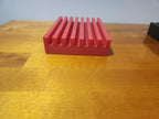 Red 3D printed slotted organizer on a wooden table, ideal for office or desk storage.