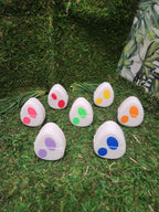 Colorful plastic egg-shaped containers with dot patterns arranged on artificial grass