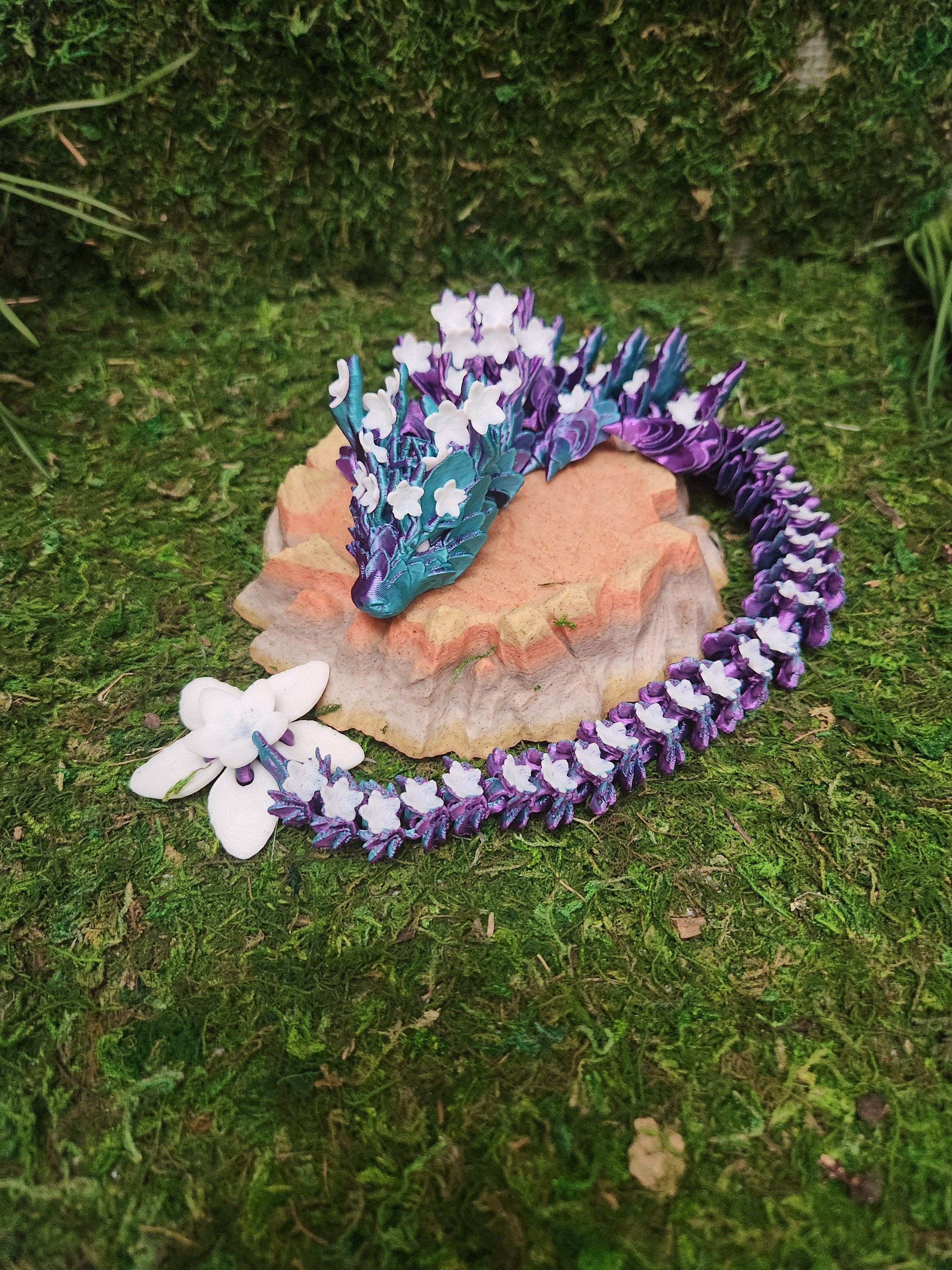 3D printed fantasy floral dragon figurine with purple and white details on mossy surface