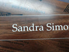 Custom engraved wood name plate with white text on a dark wood background.