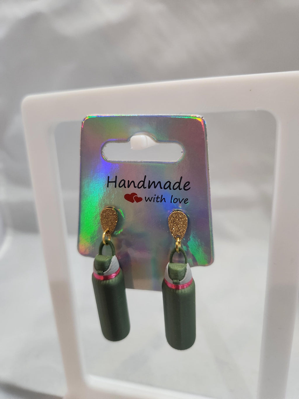 Handmade green 3D printed water bottle earrings with gold hooks on holographic card