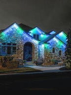 Stone house at night decorated with blue and green LED holiday lights