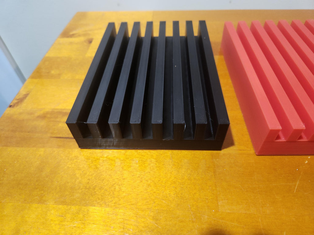 Black and red 3D printed slotted blocks on a wooden surface