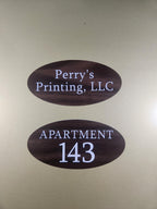 Custom oval wood-look signs with white text for apartment number and business name