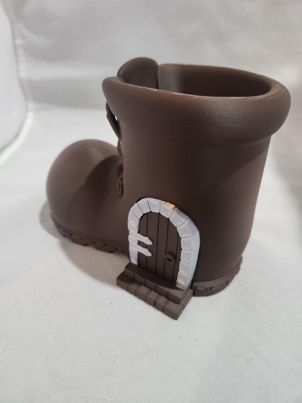 3D printed brown boot planter with a small decorative door and stone steps