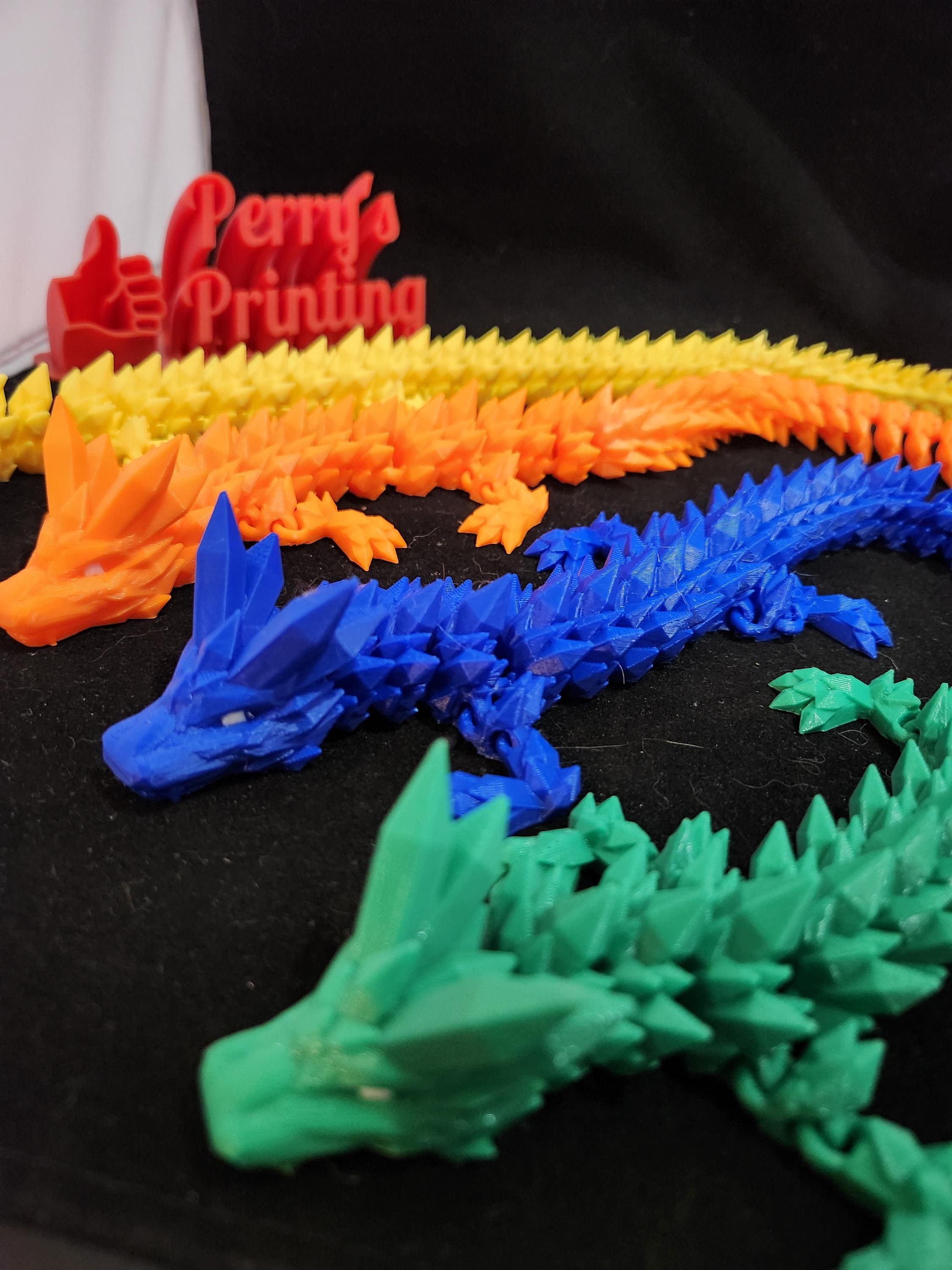 Colorful 3D printed articulated dragon figures on black background, custom printing display