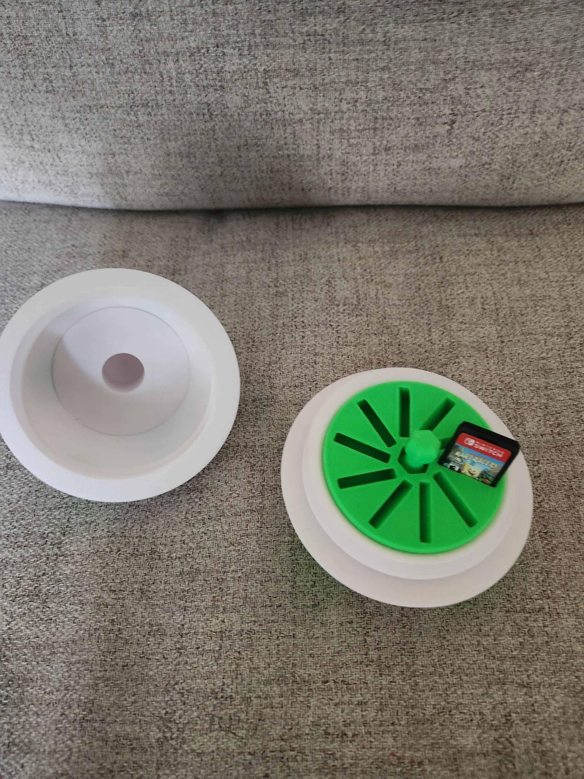 3D printed Nintendo Switch game card holder in white and green, open on gray fabric