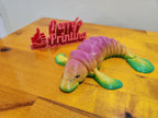 3D printed colorful articulated platypus figurine on wood table, custom sign in background