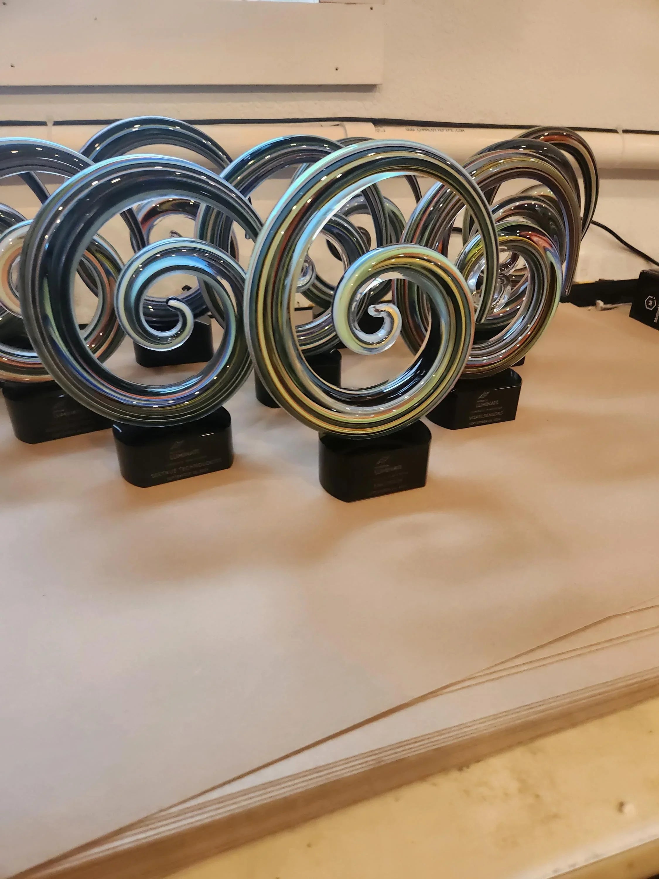 Colorful glass swirl awards with black bases, arranged on a table, for custom recognition