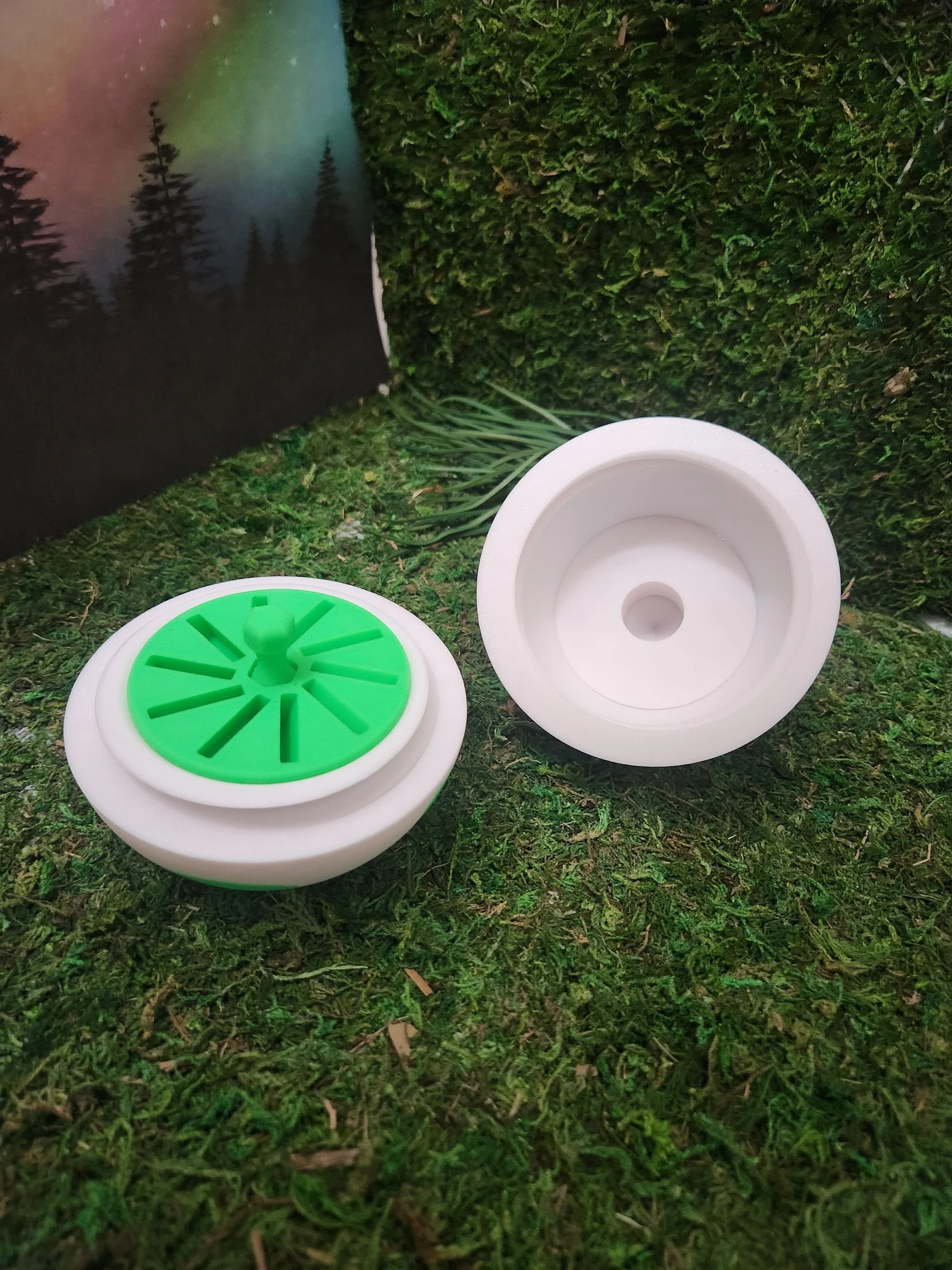 White 3D printed plastic containers with green inserts on artificial grass background