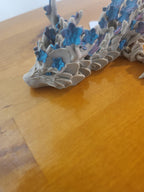 3D printed dragon figurine with blue and purple flower details on wood surface