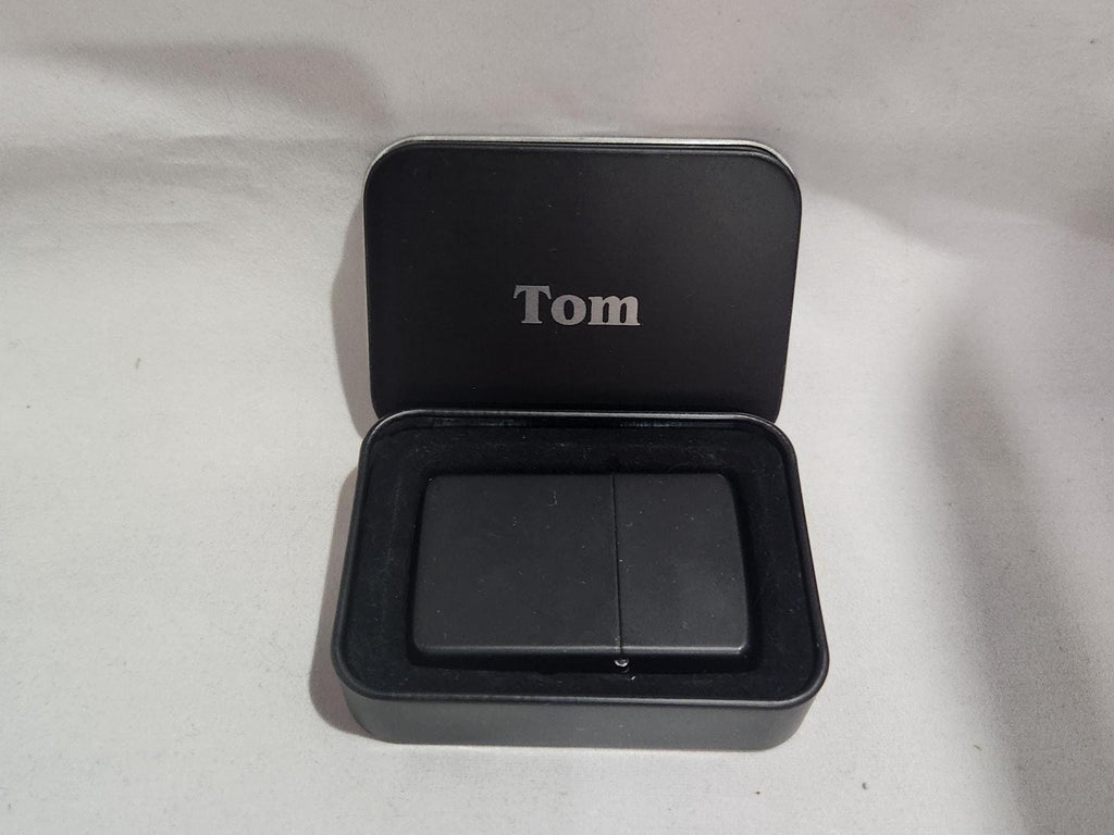 Custom engraved black lighter in a personalized metal gift box with 'Tom' inscription.