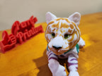 3D printed tiger figurine with detailed orange stripes on a wood surface, custom sign in background