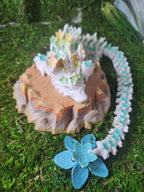 3D printed dragon figurine with floral details on a rock base, displayed on green moss
