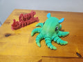 3D printed green octopus figurine and red Perry's Printing sign on wooden surface