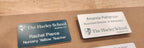 Custom printed name badges with names, titles, and The Harley School logo on a wooden surface