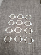 Twelve white 3D printed plastic mounting brackets arranged on a gray fabric surface