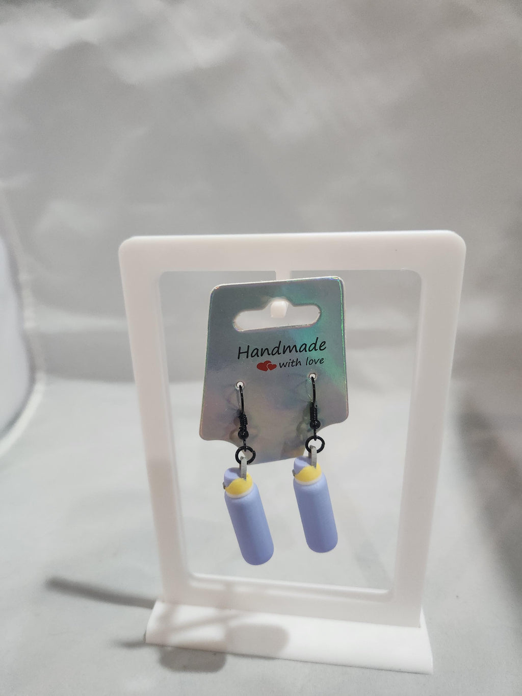 Handmade dangle earrings with light purple and yellow cylindrical design on display card