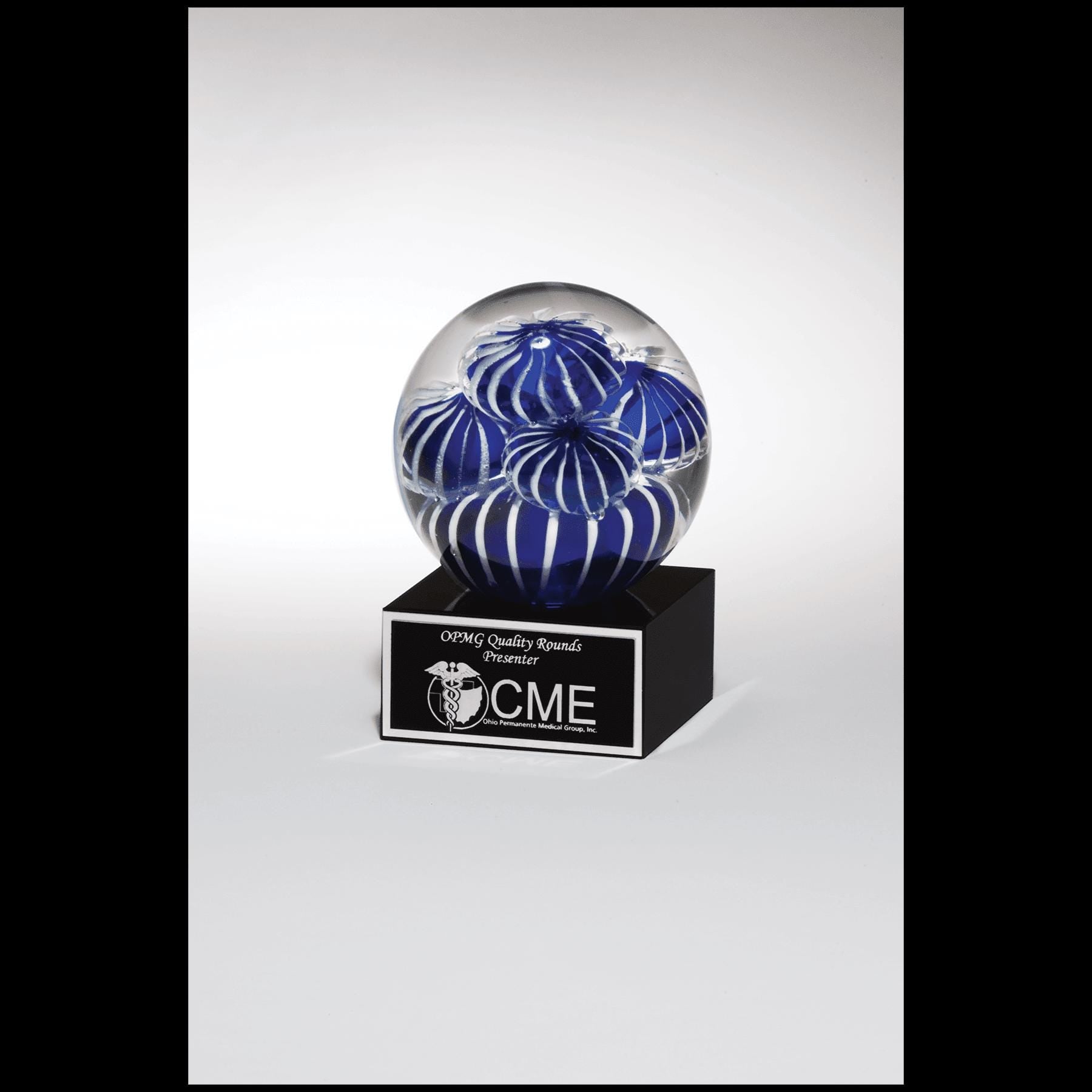 Glass award with blue and white swirl design on a black base, custom engraved plaque, CME recipient