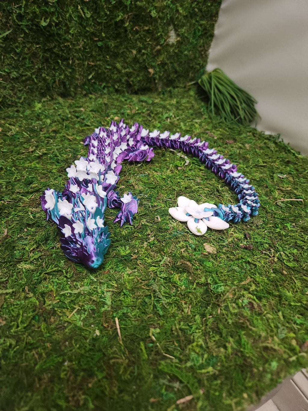 3D printed purple and blue dragon with flower accents on artificial moss background