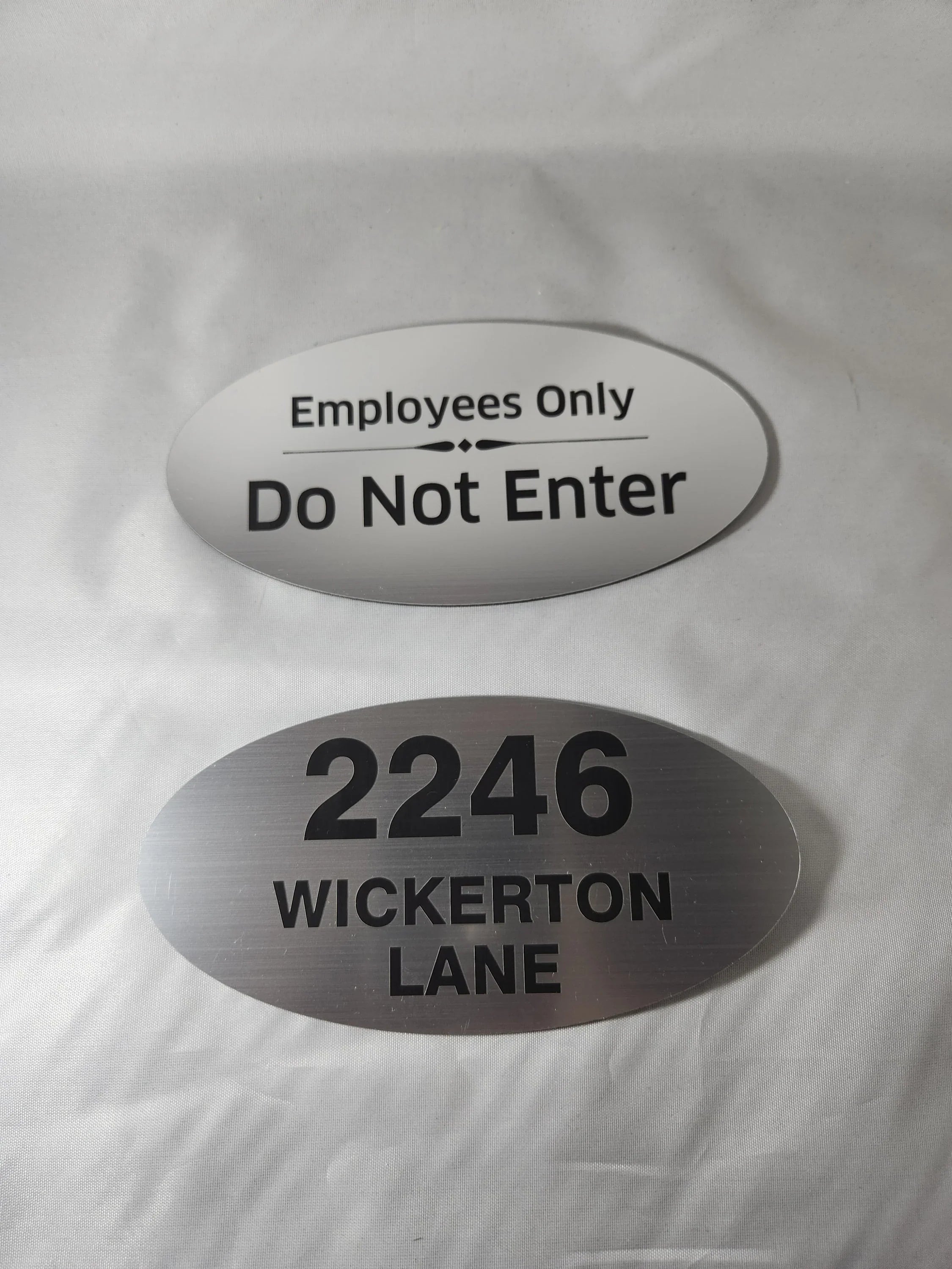 Custom engraved aluminum oval signs for employees only and house address on white background
