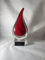 Red and clear glass flame award trophy with black engraved plate on a white background