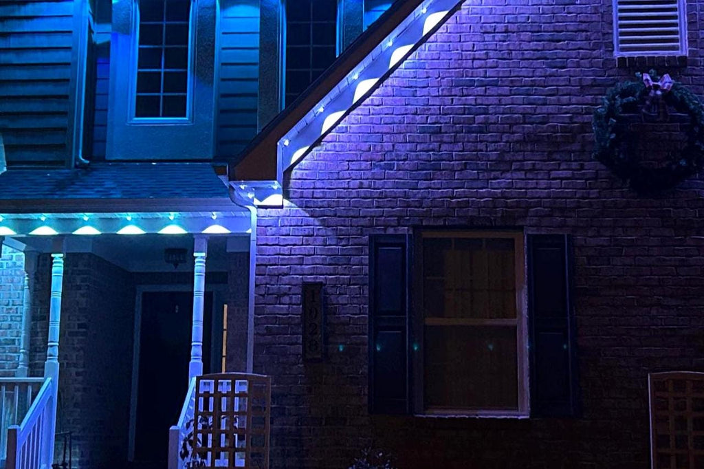 Brick house with blue LED accent lighting along roof and porch at night