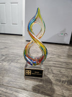 Colorful glass infinity award trophy with GSBA 2026 Impact Awards plaque on wooden floor